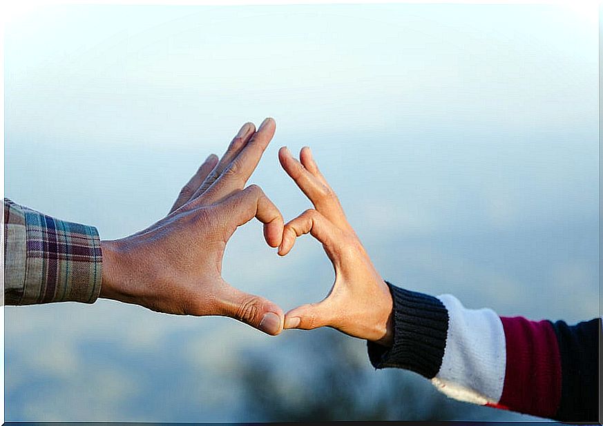 Couple forming a heart with their hands.