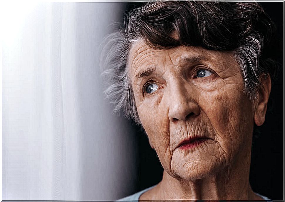 Portrait of an old woman looking out the window.