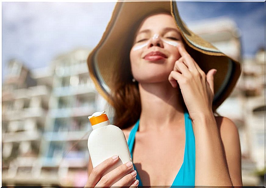 Woman putting sunscreen on her face: habits to protect the skin against cancer